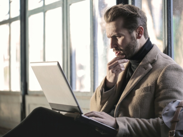 man holding his chin facing laptop computer